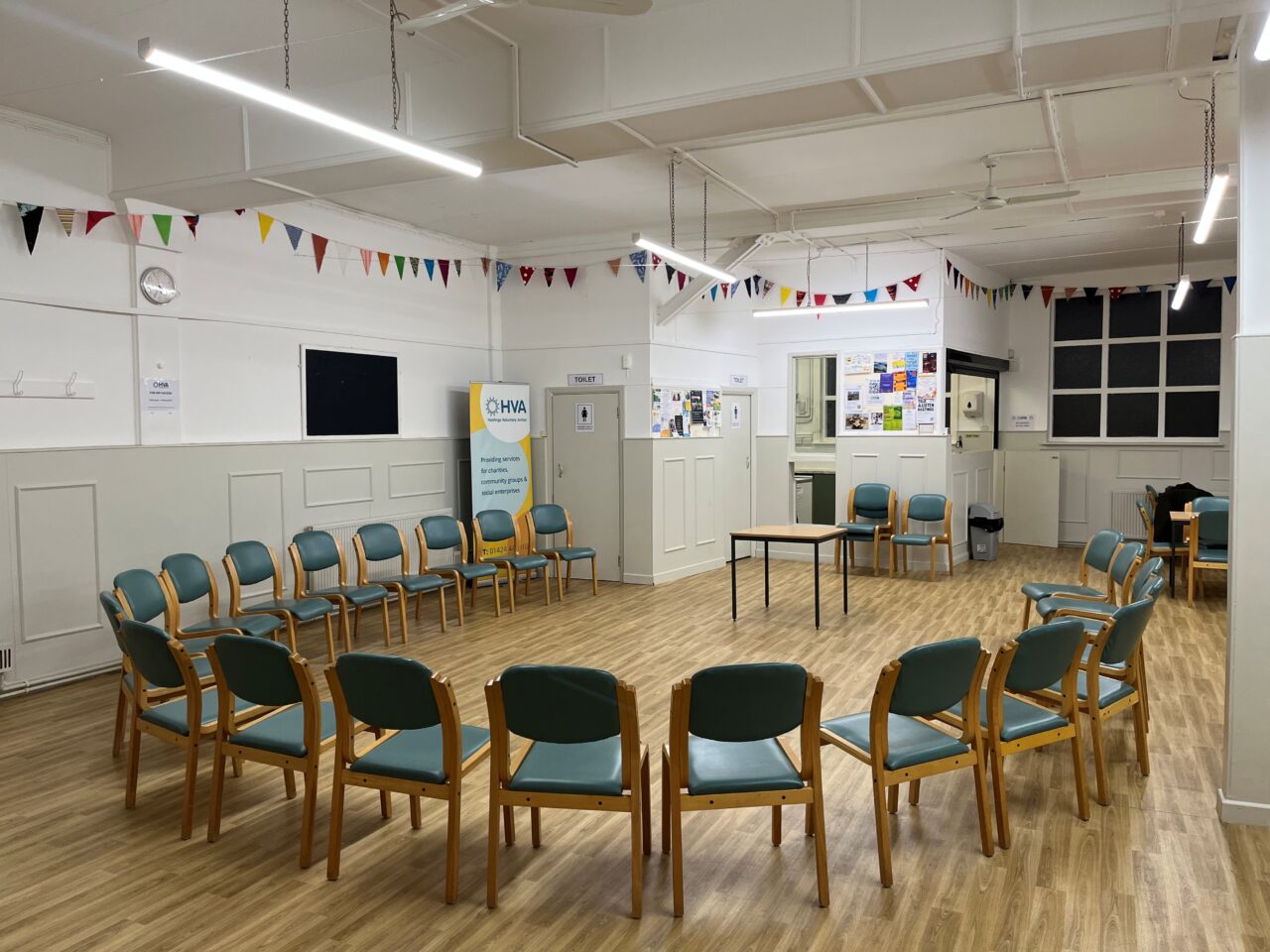 Central Hall with a lot of chairs in a horse shoe circle, facing a small table. There is bunting around the room