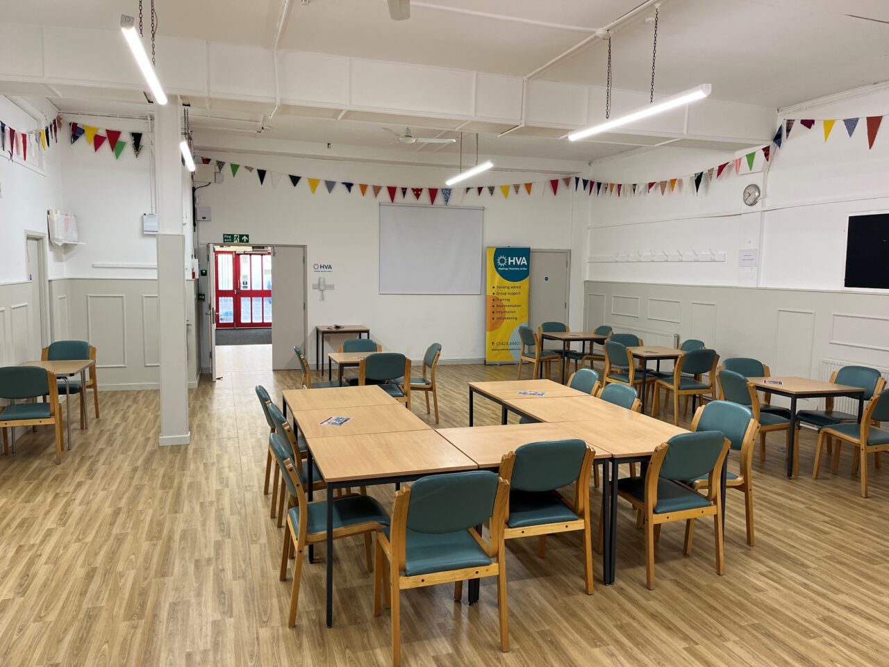 Central hall with tables and chairs set out, there is bunting hung around the room